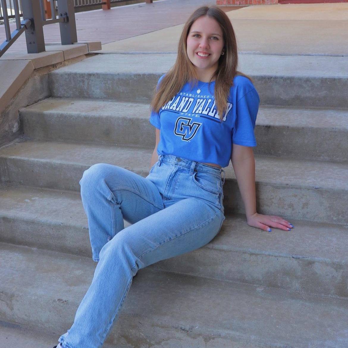 student in GVSU blue tshirt reclining on stairs